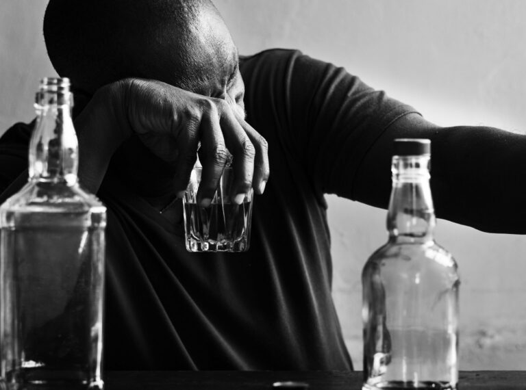 alkoholitarvitamise häirega mees depressioonis, hoiab käes klaasi alkoholiga